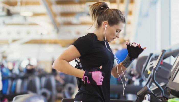 Woman running on treadmill at gym with headphones
