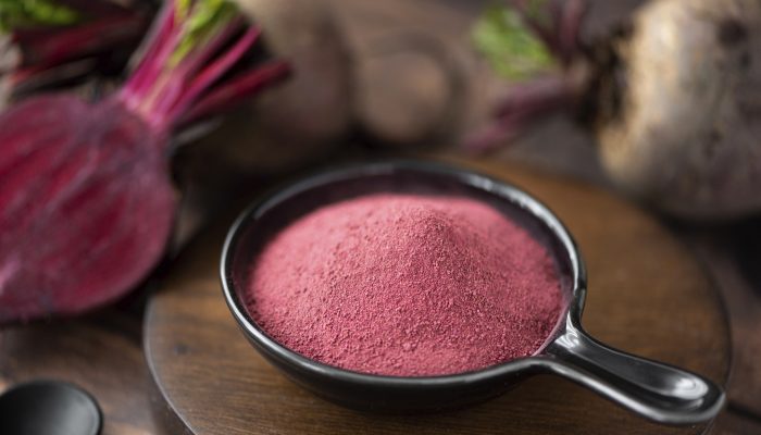 dried beetroot powder in a black bowl, close-up